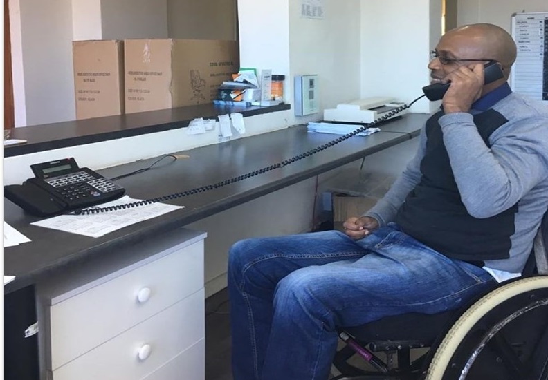 A man in a wheelchair answering the telephone at reception